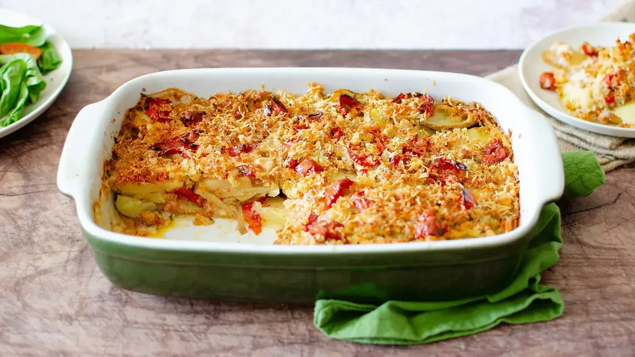 Piatto invitante di pomodori al forno alla pugliese, con patate e croccante panatura dorata.