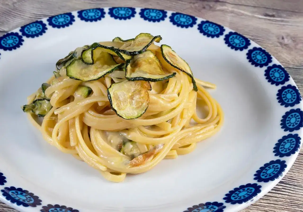 Spaghetti alla Nerano cremosi con zucchine fritte croccanti, un classico piatto italiano.