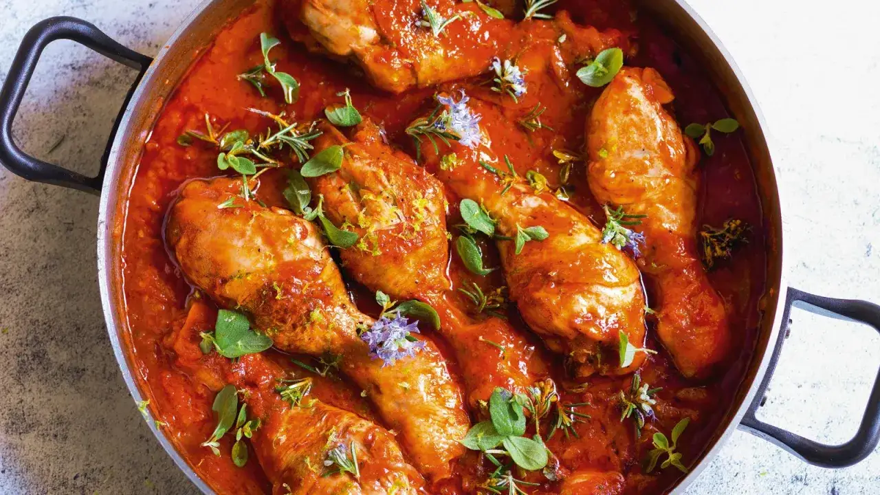 Succulento pollo alla cacciatora in padella, con erbe aromatiche e scorza di limone. Un piatto ricco e saporito, pronto per essere gustato.