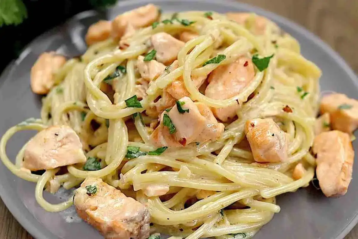 Spaghetti cremosi con succulenti pezzi di salmone e prezzemolo fresco. Un piatto di pasta con salmone invitante e saporito.