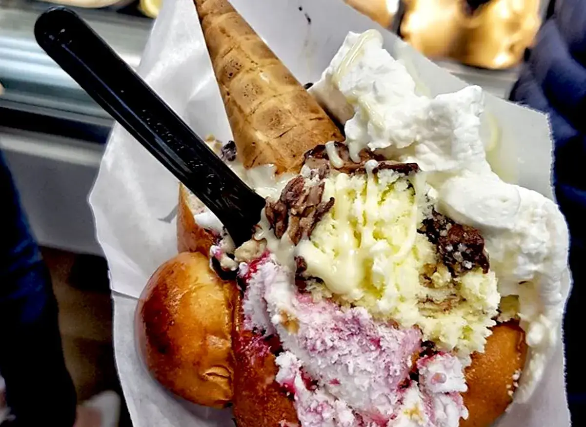Un goloso brioche col tuppo ripieno di gelato, panna e granella di cioccolato, pronto per essere gustato.