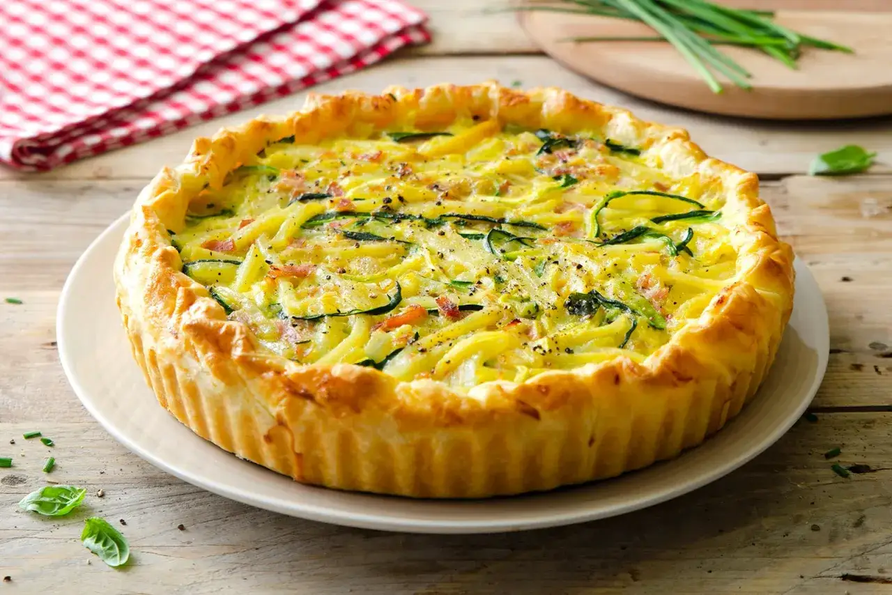 Deliziosa torta salata estiva con zucchine e pancetta, dorata e invitante, pronta per essere gustata.