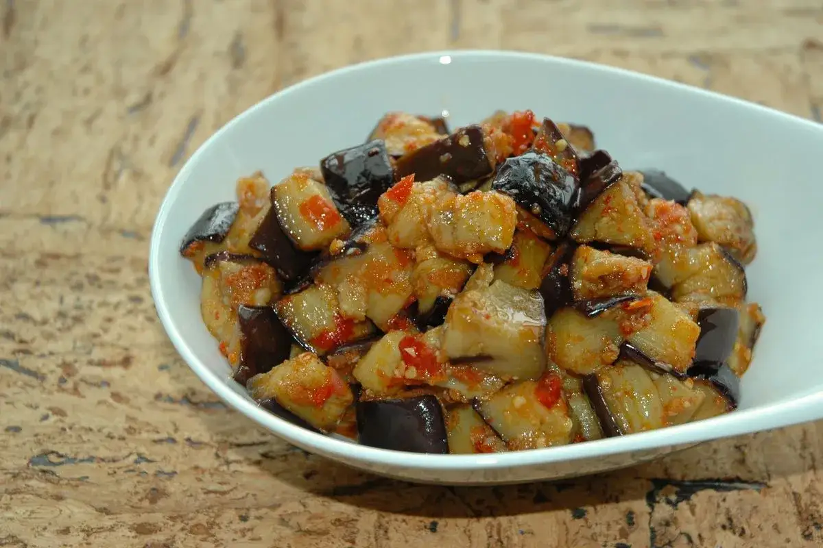Melanzane al microonde, un contorno saporito e veloce. Pezzetti di melanzane conditi con pomodoro e spezie, pronti da gustare.
