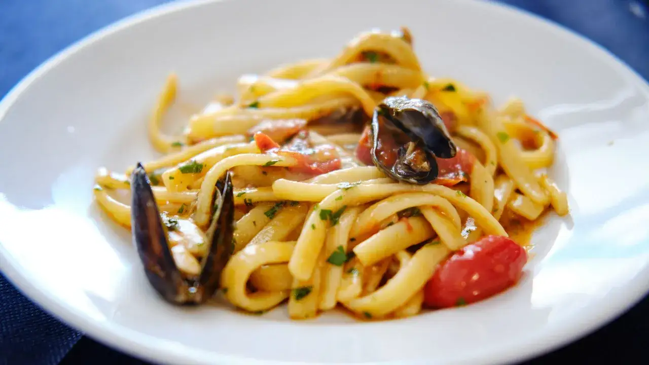 Scialatielli ai frutti di mare, un piatto invitante con cozze, pomodorini e prezzemolo su pasta fresca.