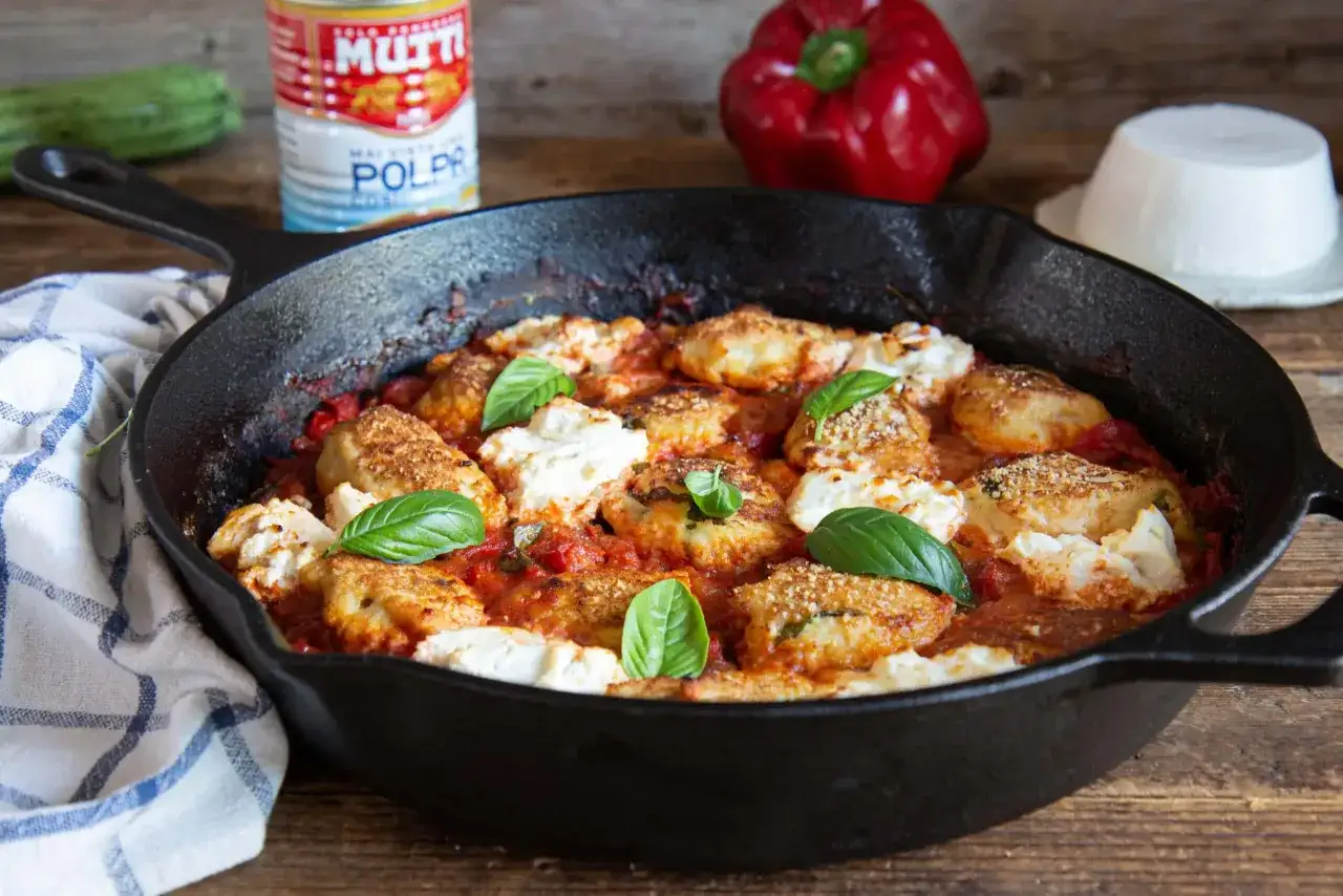 Polpette di pollo al sugo con ricotta e basilico, servite in padella. Ingredienti freschi e profumati per un piatto gustoso.