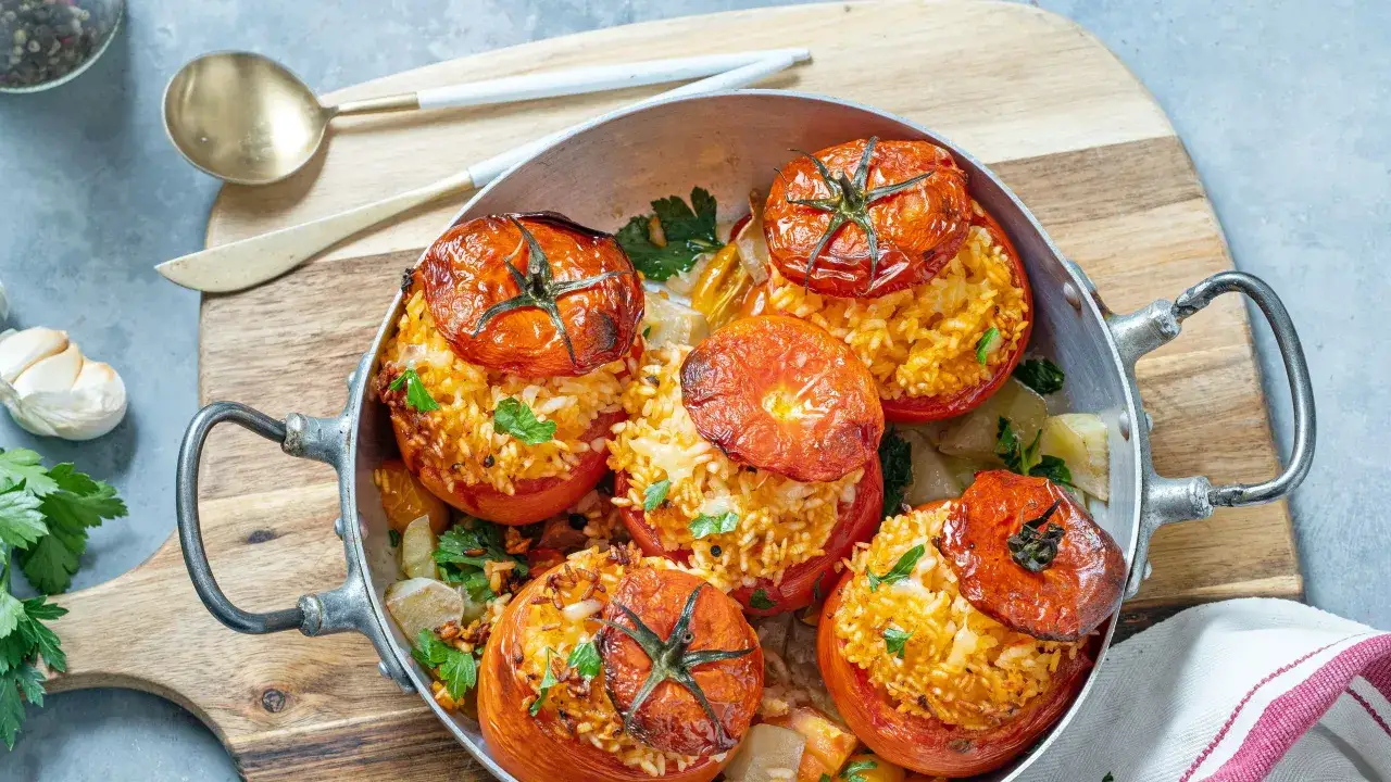 Pomodori ripieni freddi, un piatto estivo saporito con riso e erbe aromatiche, serviti in una padella metallica.