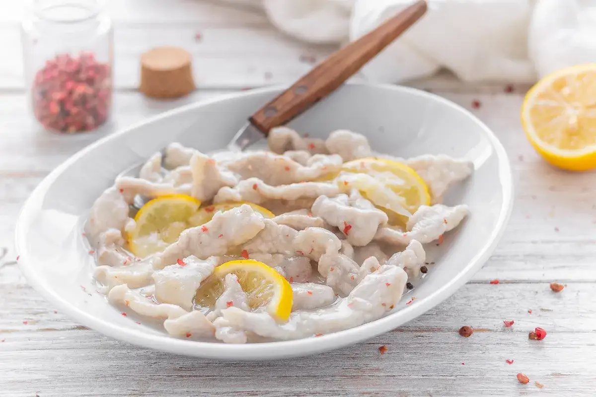 Straccetti di vitello teneri e succulenti, conditi con fette di limone fresco e pepe rosa. Un piatto semplice ma gustoso.