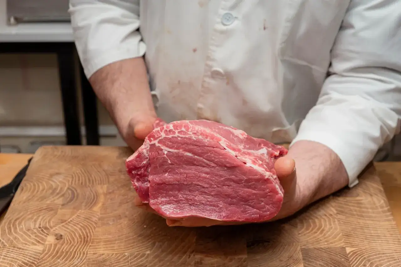 Mani che sorreggono un succulento filetto di manzo crudo, pronto per essere cucinato.