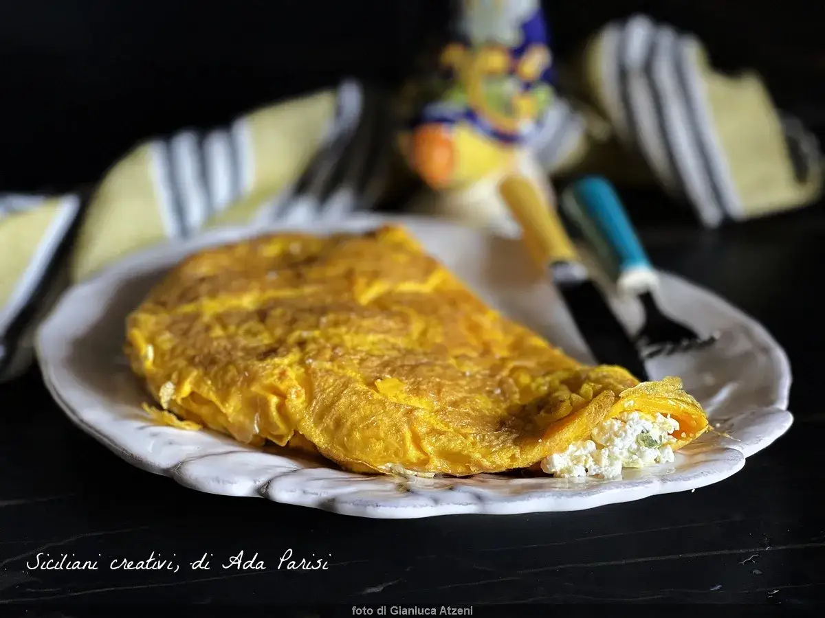 Frittata di ricotta alla siciliana, soffice e dorata, servita su un piatto bianco. Un assaggio di Sicilia!
