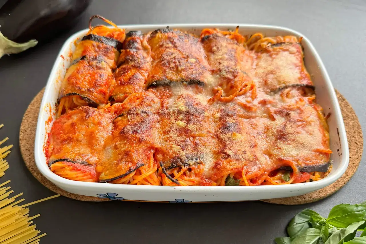 Involtini di melanzane con spaghetti al forno, ricchi di sugo e formaggio filante, pronti per essere gustati.