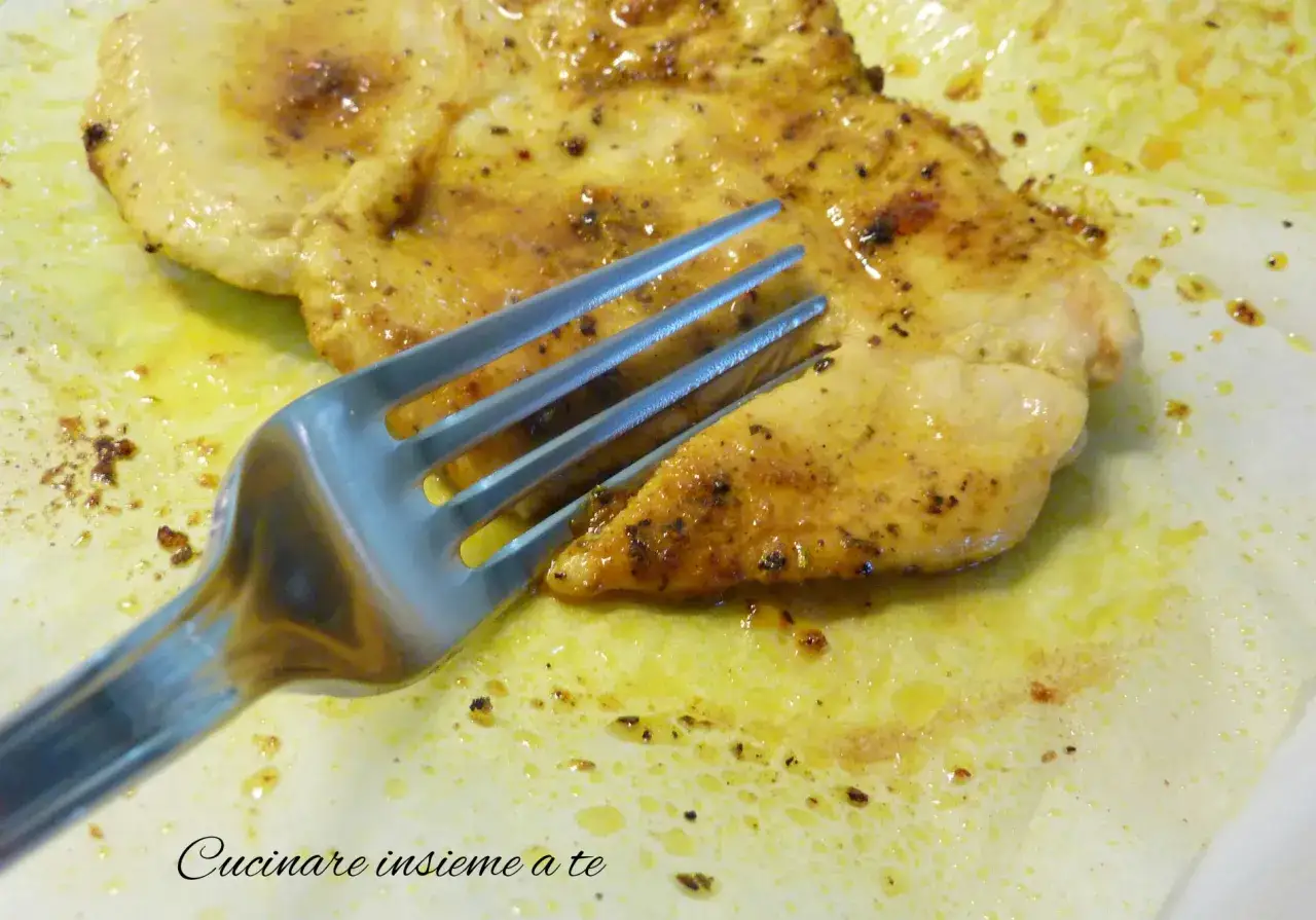 Un succulento petto di pollo dorato, condito con spezie, pronto per essere gustato con una forchetta.