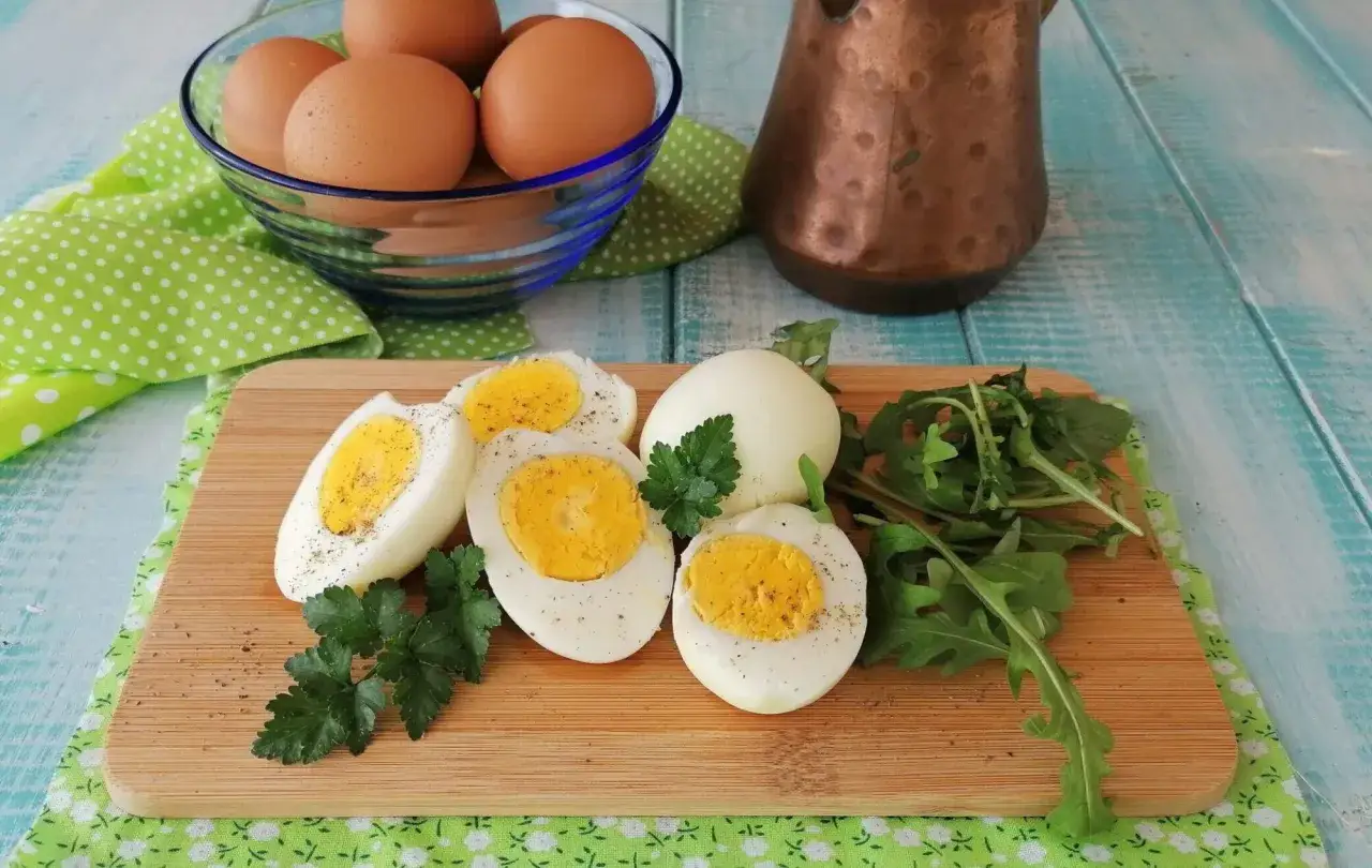Uova sode perfette, cotte in friggitrice ad aria, servite su tagliere con rucola e prezzemolo.