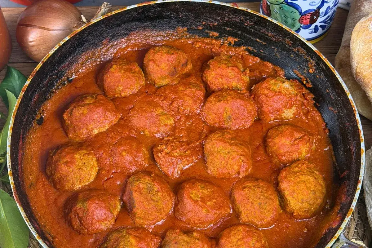 Polpette al limone succulente in padella, immerse in un sugo rosso vibrante. Un piatto che profuma di casa e tradizione.