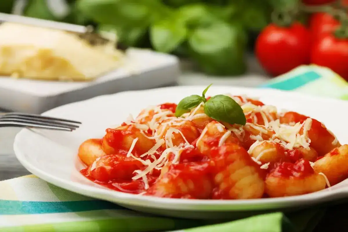 Gnocchi al pomodoro, un piatto semplice e gustoso, con basilico fresco e parmigiano grattugiato.