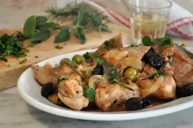 Piatto di coniglio alla cacciatora in bianco, con olive verdi e nere, cipolle e rosmarino.