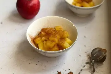 Mele cotte in pentola, dolci e profumate alla cannella, servite in una ciotola.