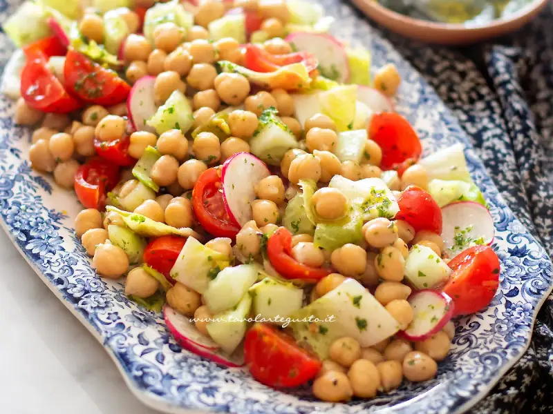 Deliziosa insalata di ceci fredda con pomodorini, cetrioli e ravanelli, condita con erbe fresche. Perfetta per un pasto leggero e gustoso.
