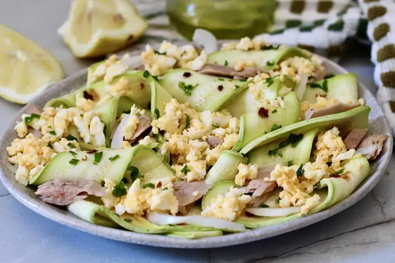 Deliziosa insalata di zucchine crude a nastro, condita con tonno, uova sode sbriciolate e prezzemolo fresco.