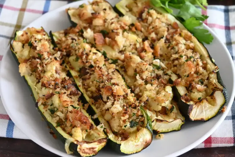 Zucchine ripiene al forno, dorate e croccanti, con un ripieno saporito e erbe aromatiche. Un piatto invitante e gustoso.