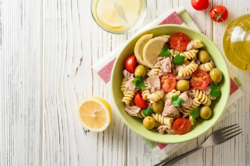 Deliziosa pasta fredda con tonno, pomodorini, olive e limone, perfetta per un pasto estivo.